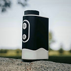 SEASONS rangefinder resting on stone with a golf course in the background