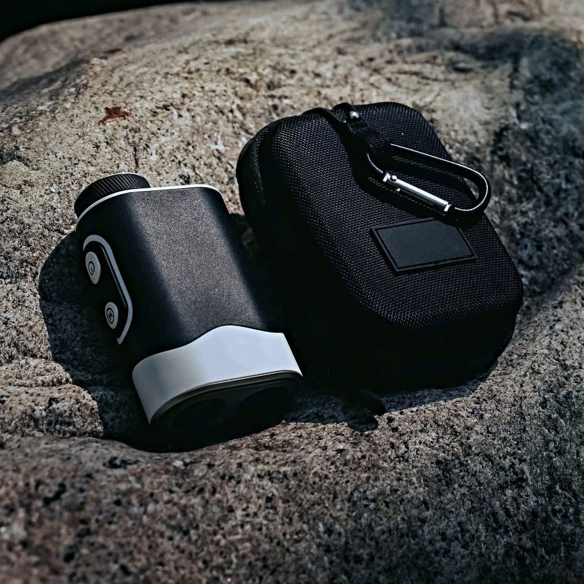 SEASONS rangefinder beside its zip carrying case with carabiner clip, on granite